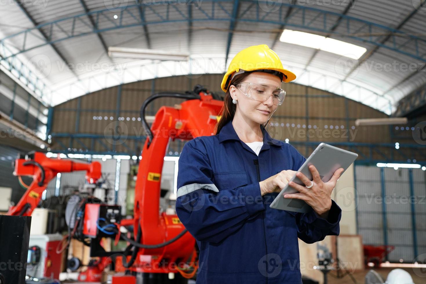 porträtt av en professionell ingenjörsarbetare för tung industri som bär uniform, glasögon och hjälm i en stålfabrik. vacker kvinnlig industrispecialist som står i metallkonstruktionsanläggning. foto