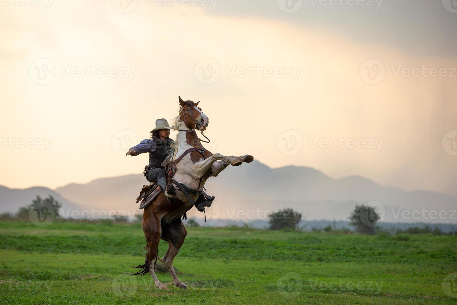 cowboy ridhäst med hand som håller pistol mot solnedgången bakgrund. foto