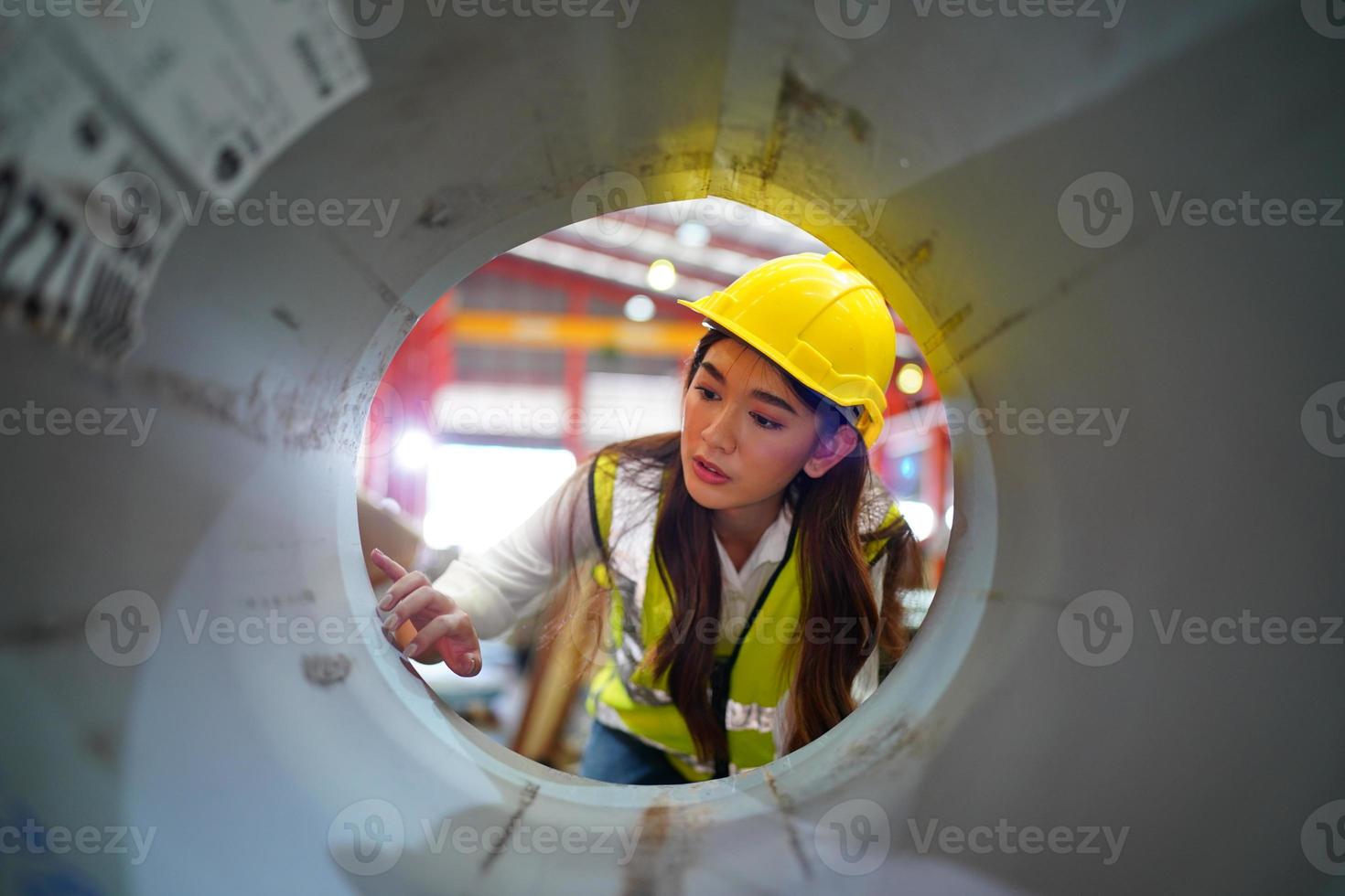 kvinnlig arbetare förman eller arbetare arbete på fabriksplatsen kontrollera maskin eller produkter på plats. ingenjör eller tekniker som kontrollerar material eller maskin på anläggningen. industri och fabrik. foto