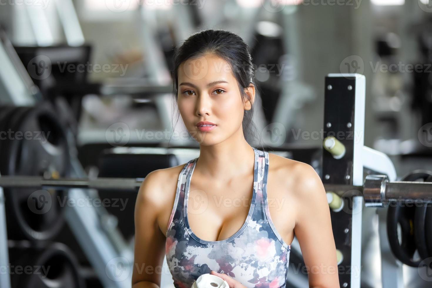 ung asiatisk kvinna träning och träning på gym. foto