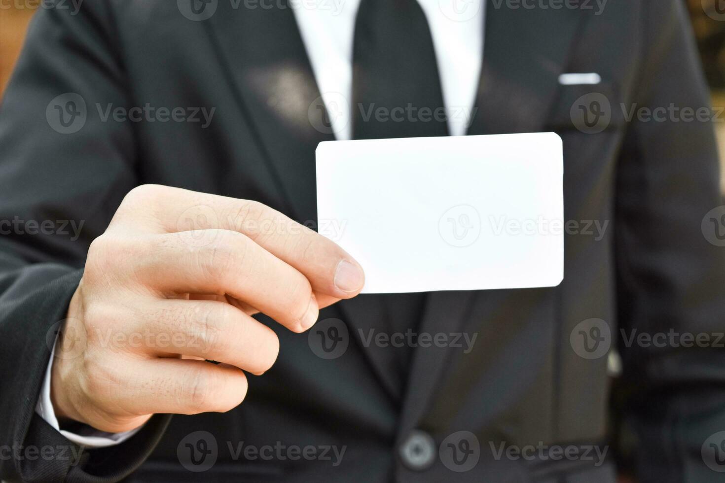 närbild av affärsman visar vitt papper i svart kostym. idé för affärskreditkort eller visitkort. foto