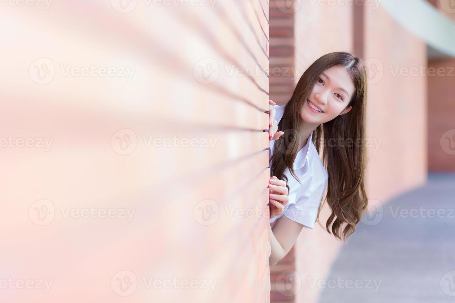 porträtt av en vuxen thai student i universitetsstudentuniform. asiatisk vacker flicka står och ler glatt på universitetet foto