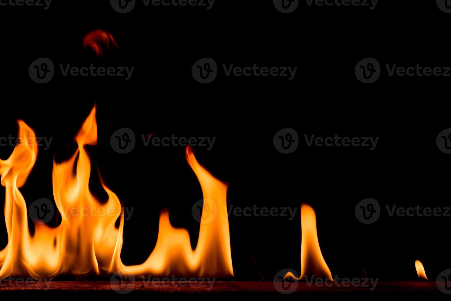 natur eld lågor på svart bakgrund. frysrörelse av röd-gula eldslågor som brinner på mörk natt. foto