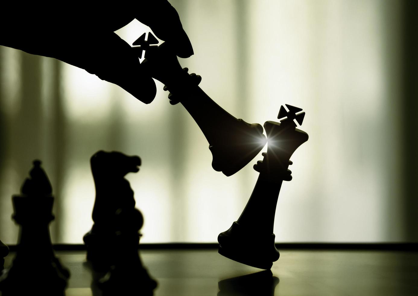 hand som håller svart kung attack vit kung av schack silhuetter strid ombord. svart kung är ledare för att slåss med lagarbete till seger. ledare, strategi och schackmatt koncept för framgång. foto