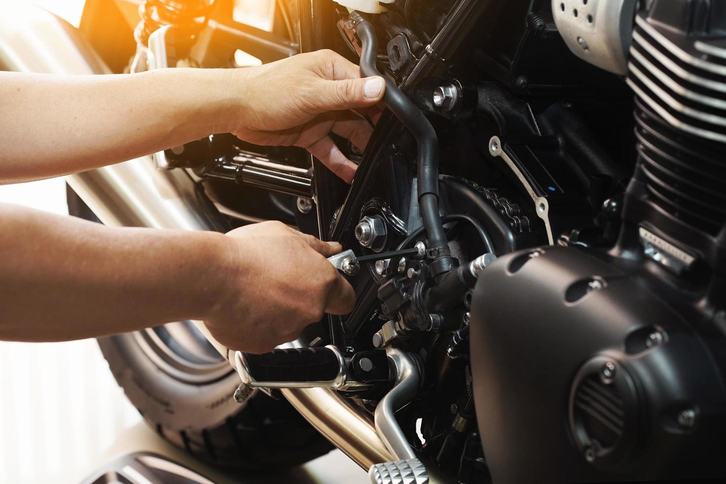 mekaniker håller sexkantnyckel som arbetar på motorcykel på motorcykelgarage, koncept för motorcykelunderhåll och reparation.selektivt fokus foto