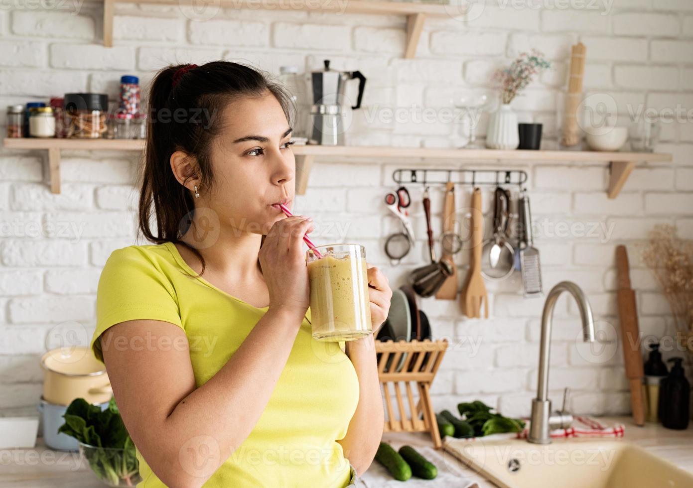 ung brunett kvinna dricker frukt banan smoothie hemma kök foto