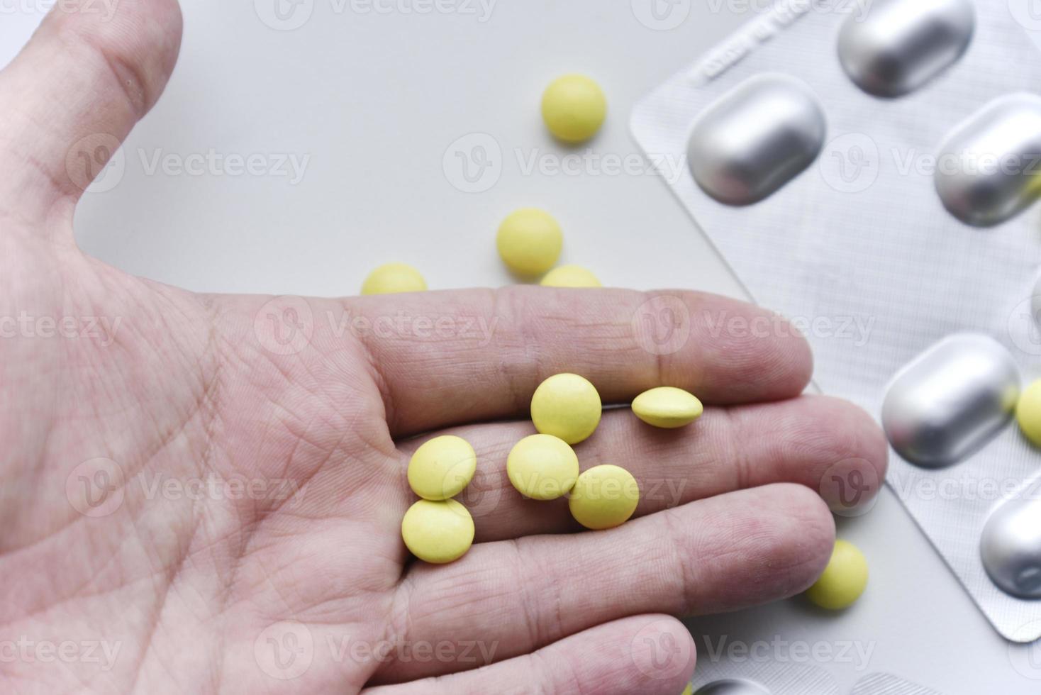 gula piller i handflatan på en vit bakgrund foto