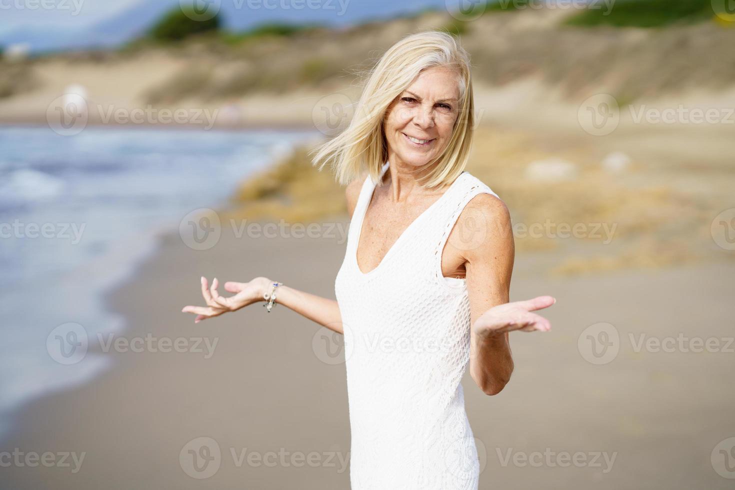 leende mogen kvinna går på stranden, spenderar sin fritid, njuter av sin fritid foto
