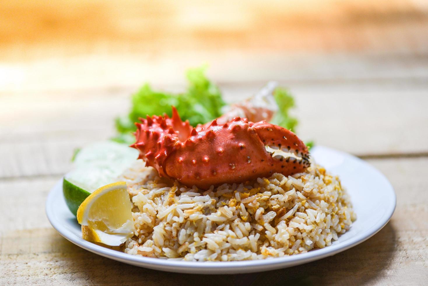 stekt ris krabba skaldjur hälsosam mat stekt ris med krabbaklo med ägg citron och gurka på vit tallrik träbord foto