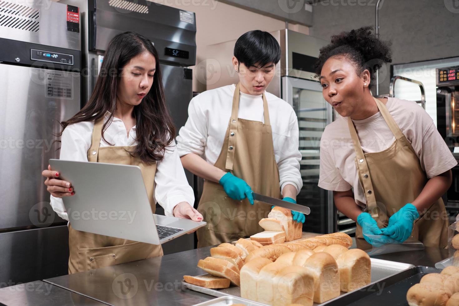 tre unga vänner och nystartade partners för bröddeg och konditorivaror upptagna med hemlagade bakjobb medan de lagar beställningar online, packar och levererar i bageributik, småföretagare foto