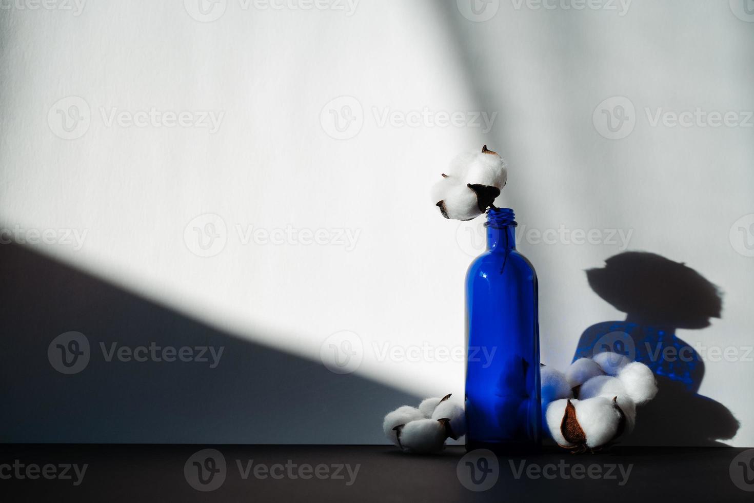 blå glasflaska med flera bomullsblommor foto