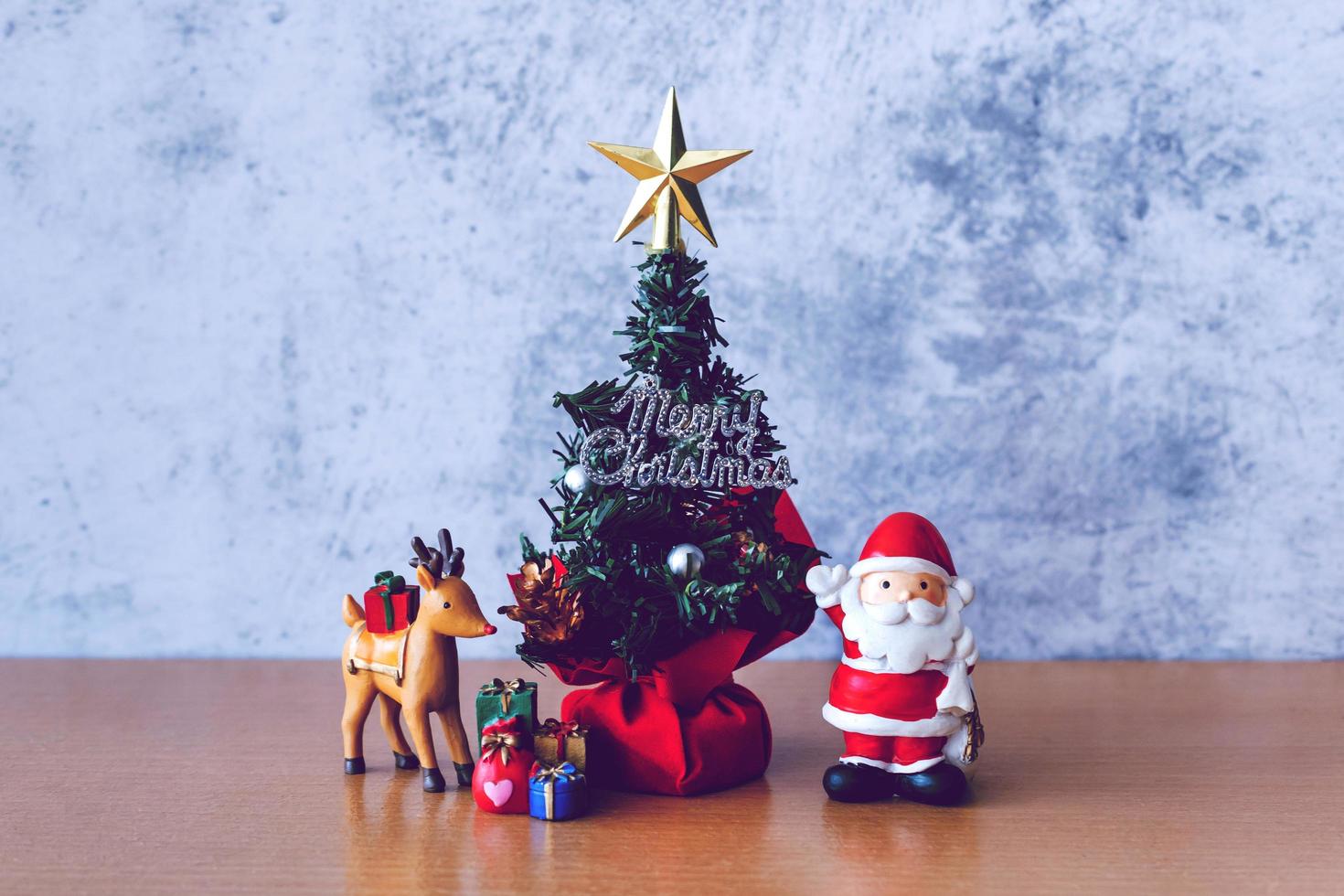 juldekoration - jultomten, träd och gåva på träbord. jul och gott nytt år koncept foto