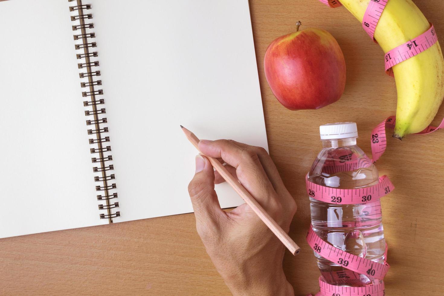 hälsosam kost koncept, måttband, frukt och vattenflaska på en trä bakgrund, tom kopia utrymme anteckningsbok foto