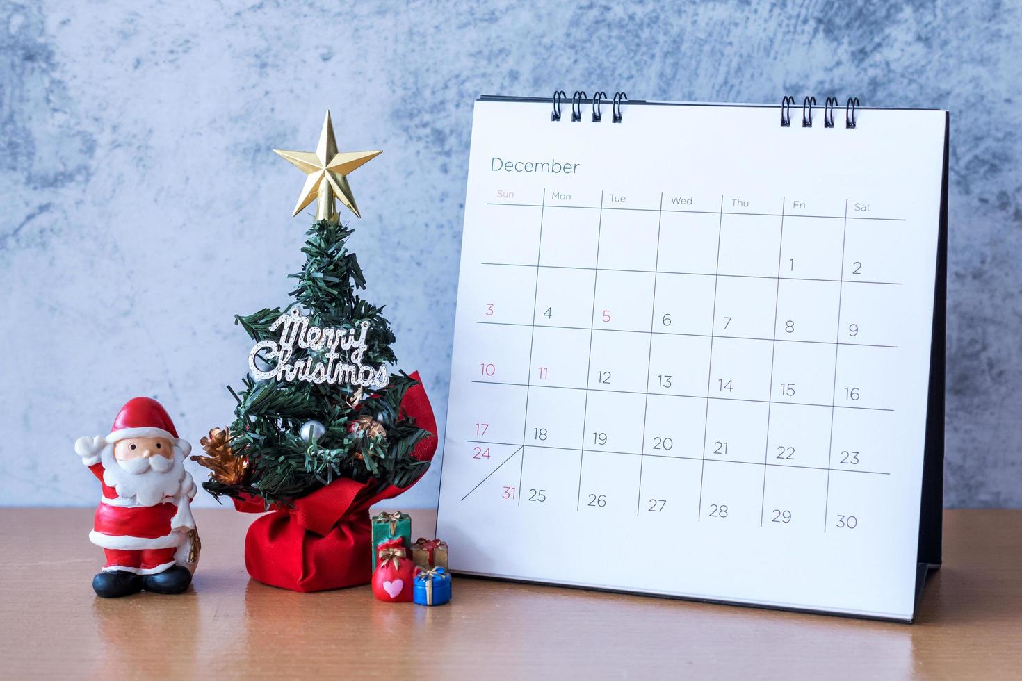 December kalender och juldekoration - jultomten, träd och present på träbord. jul och gott nytt år koncept foto