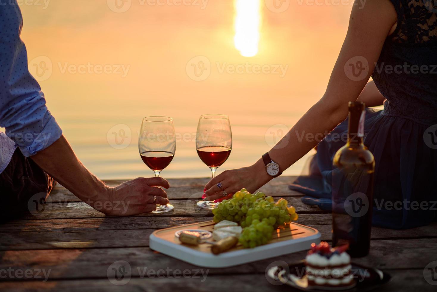 man och kvinna klingande vinglas på bakgrunden av färgglada sommarsolnedgången foto