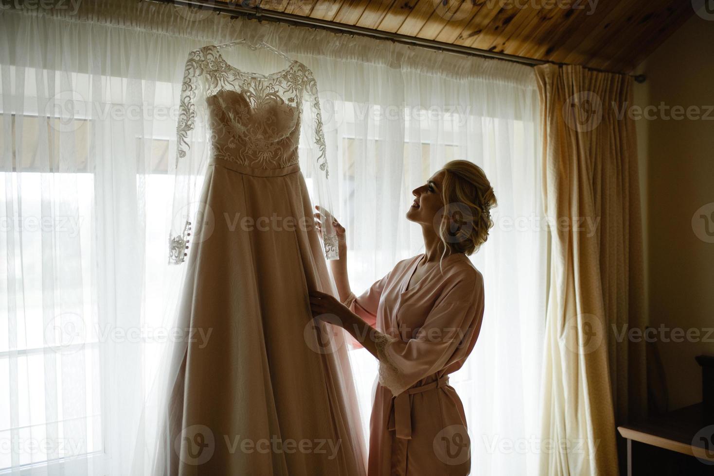 brud i nattklänning som håller sin bröllopsklänning i skugga foto