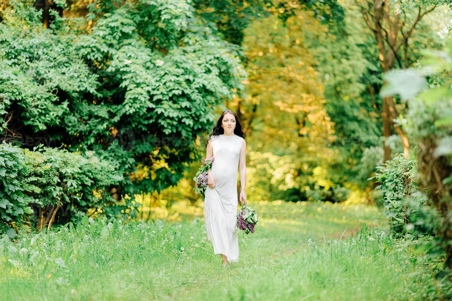 lycklig gravid kvinna i en krans och en bukett vilda blommor o foto