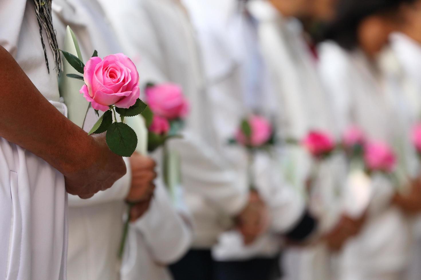 grupp människor som erbjuder rosenblomma som uttrycker kondoleans för att respektera den förlorade kärleken under sorgceremonin på begravningen foto