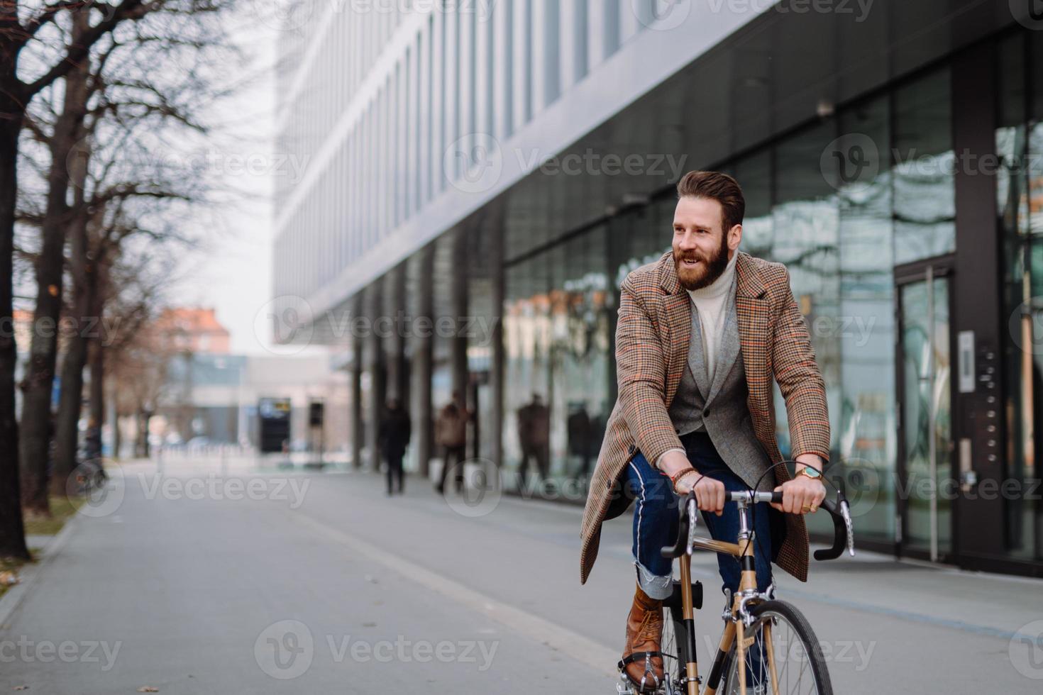 ung hipster affärsman kommer att arbeta på cykel. miljövänligt transportkoncept foto