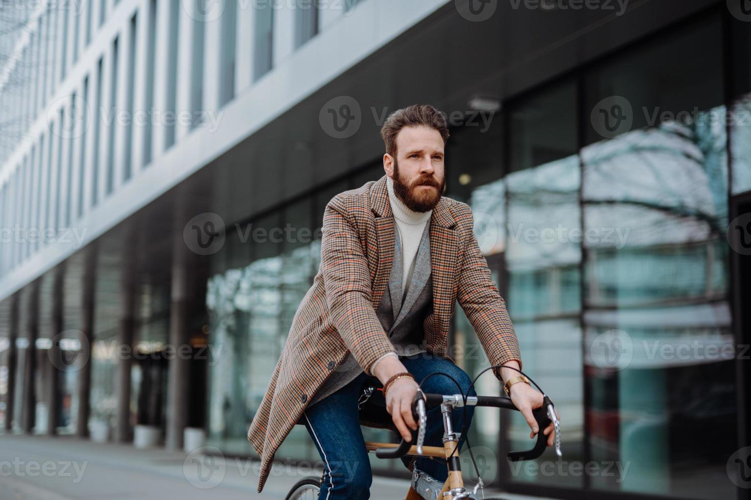 ung hipster affärsman kommer att arbeta på cykel. miljövänligt transportkoncept foto