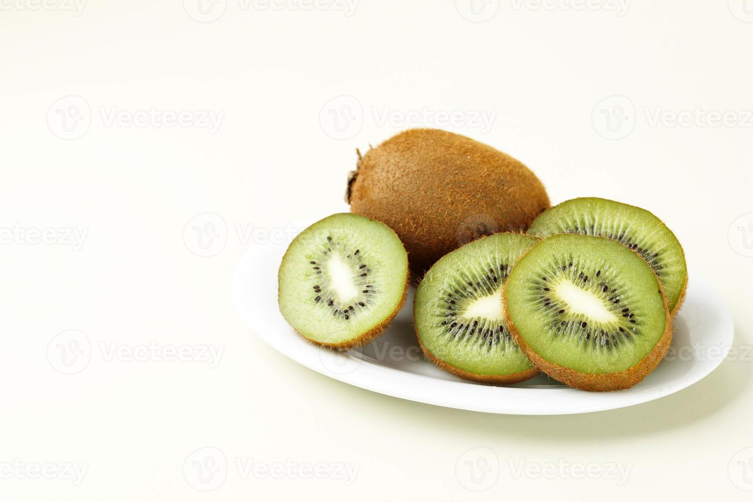 mogen skivad grön kiwi på vit platta foto