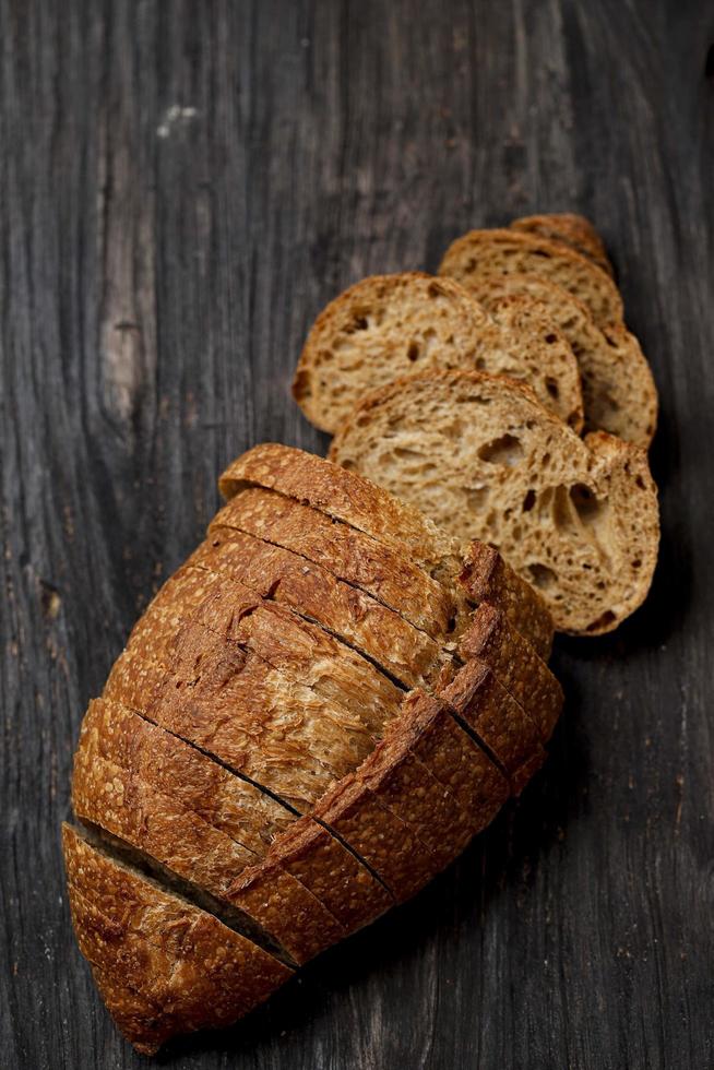 läckra hemlagade skivat bröd på mörk trä rustik bakgrund. foto