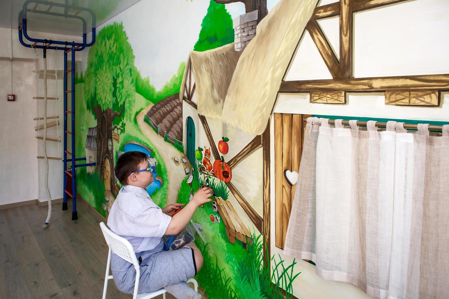 redaktionell. en tonårspojke med funktionshinder leker med bilder på en magnettavla. downs syndrom, autism. rehabiliteringscenter, skola för specialbarn. kaluga, Ryssland, 21.06.2018 foto