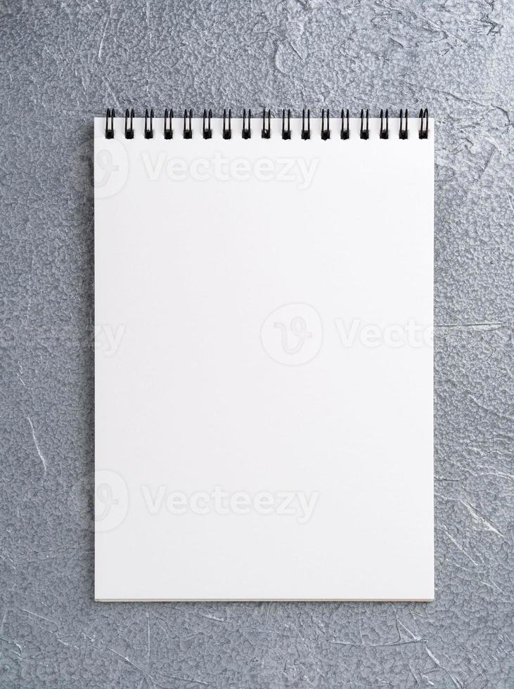 tomt ark av anteckningsboken med en spiral på en neutral grå texturerad silvermetallisk bakgrund foto