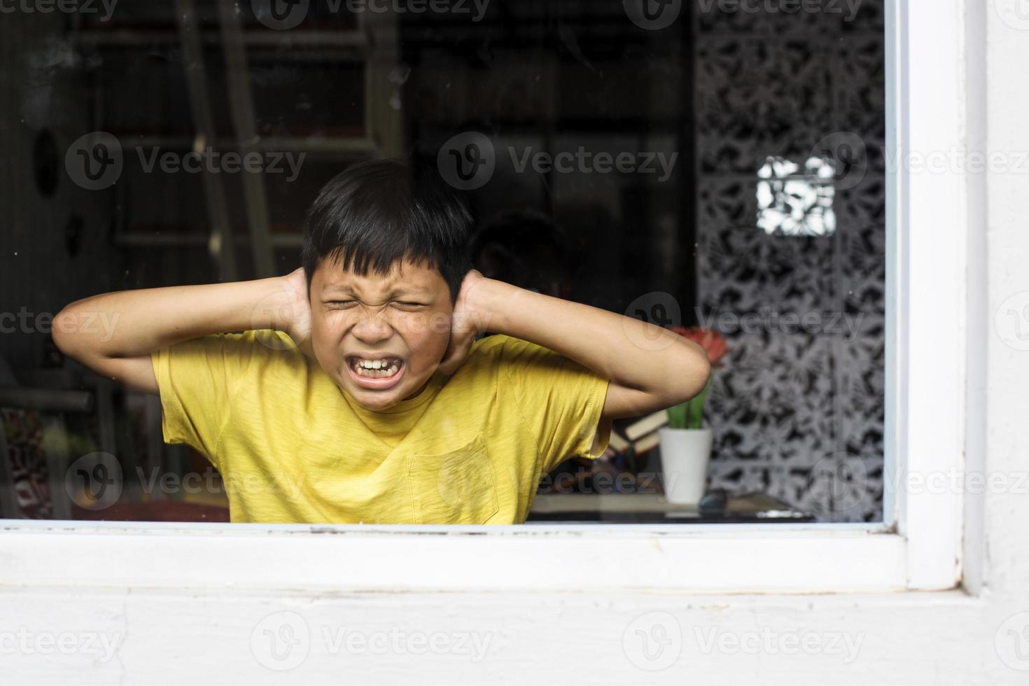 asiatisk pojke stänger öronen med händerna i en skyddande position. traumatisk upplevelse i barndomen, psykologi, psykologisk, aspergers syndrom, aspergers sjukdom, autism, autism. foto