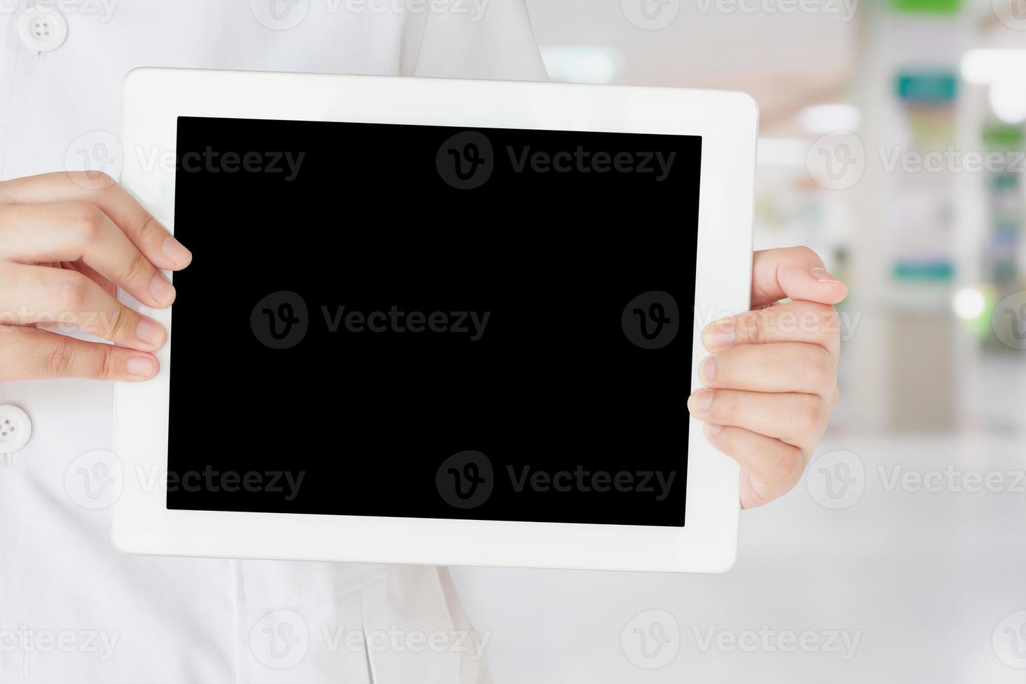 kvinnlig läkare som håller tom digital surfplatta med sjukhusinteriörbakgrund foto