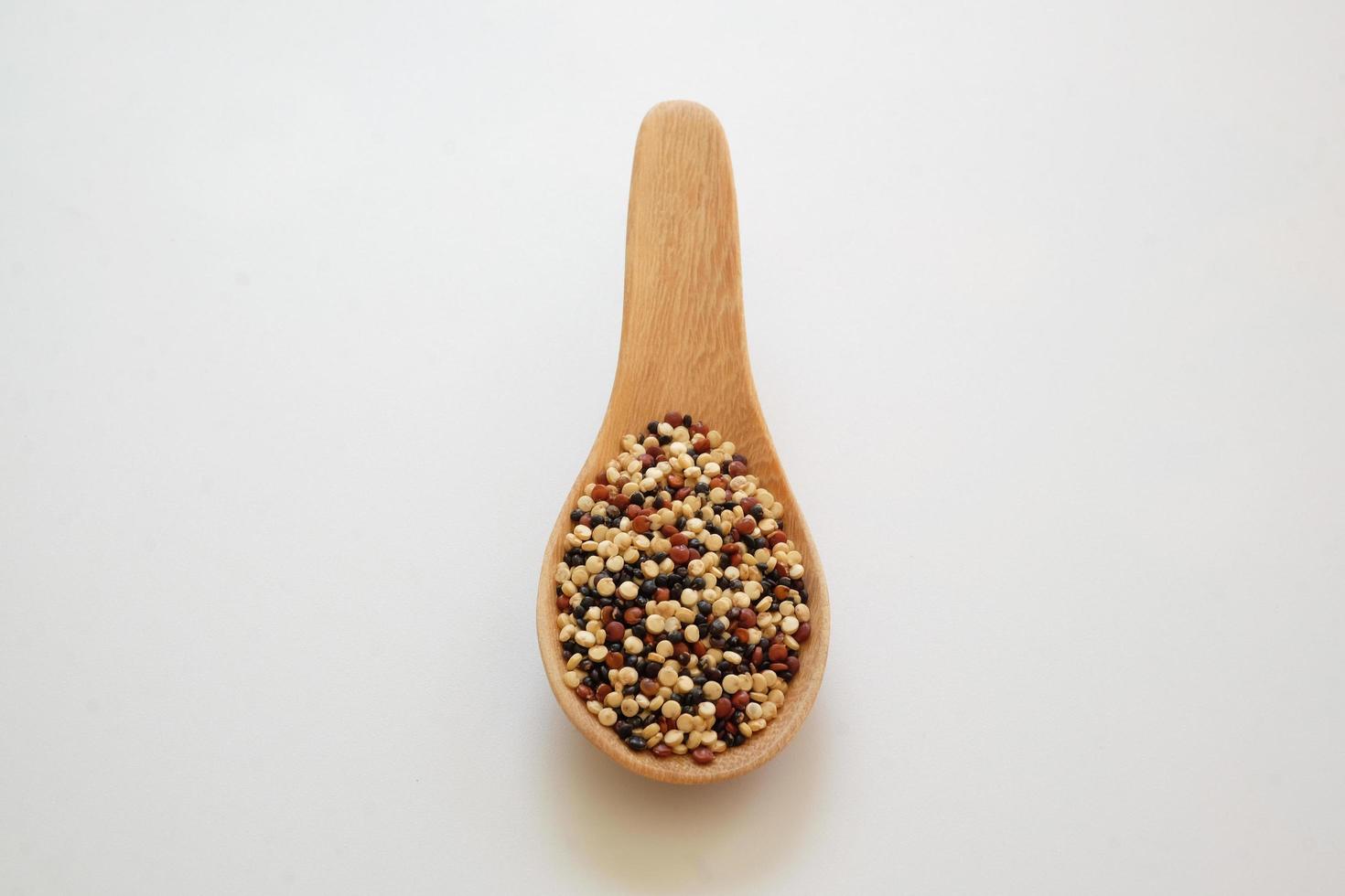 quinoa frön i träskeden isolerad på vit bakgrund. quinoa är en bra proteinkälla för människor som följer en växtbaserad kost. foto