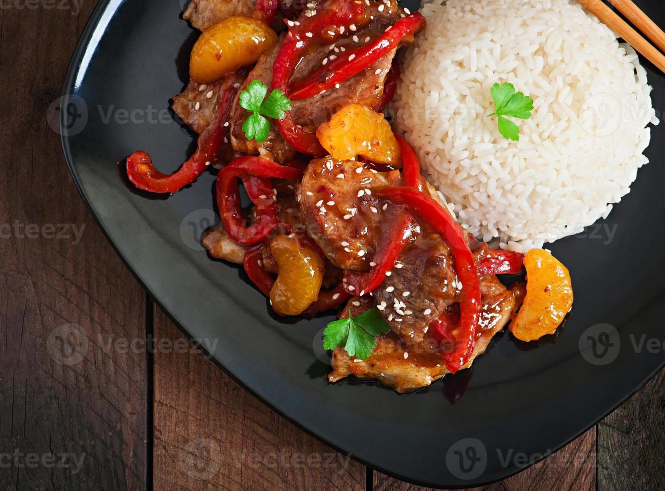 kött i en kryddig sås, paprika och mandariner med garnering av kokt ris foto