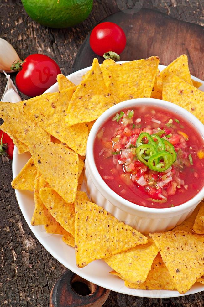 mexikanska nachochips och salsa dopp i skål på trä bakgrund foto