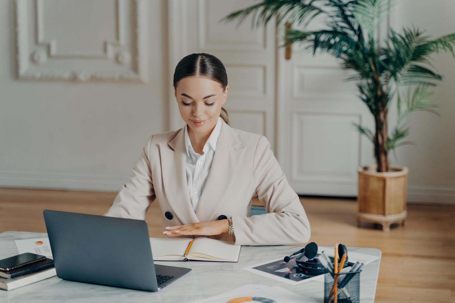 koncentrerad affärskvinna sitter vid skrivbordet framför laptop foto