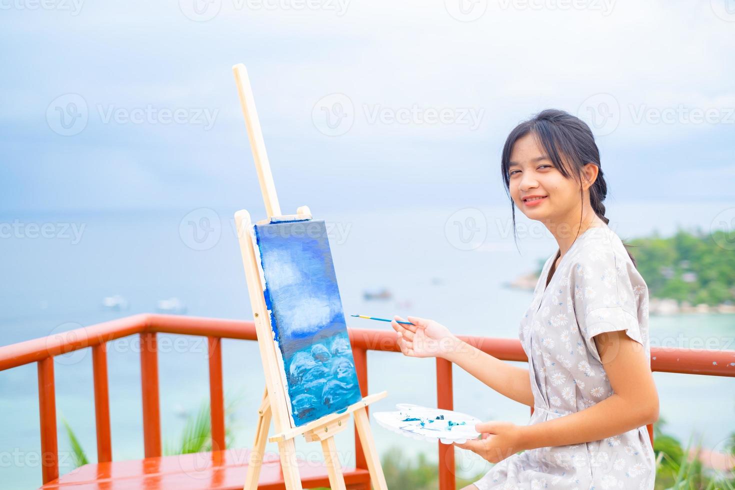 ung flicka med penselteckning på dukpapper, vid vacker landskapsvy på koh tao thailand. foto