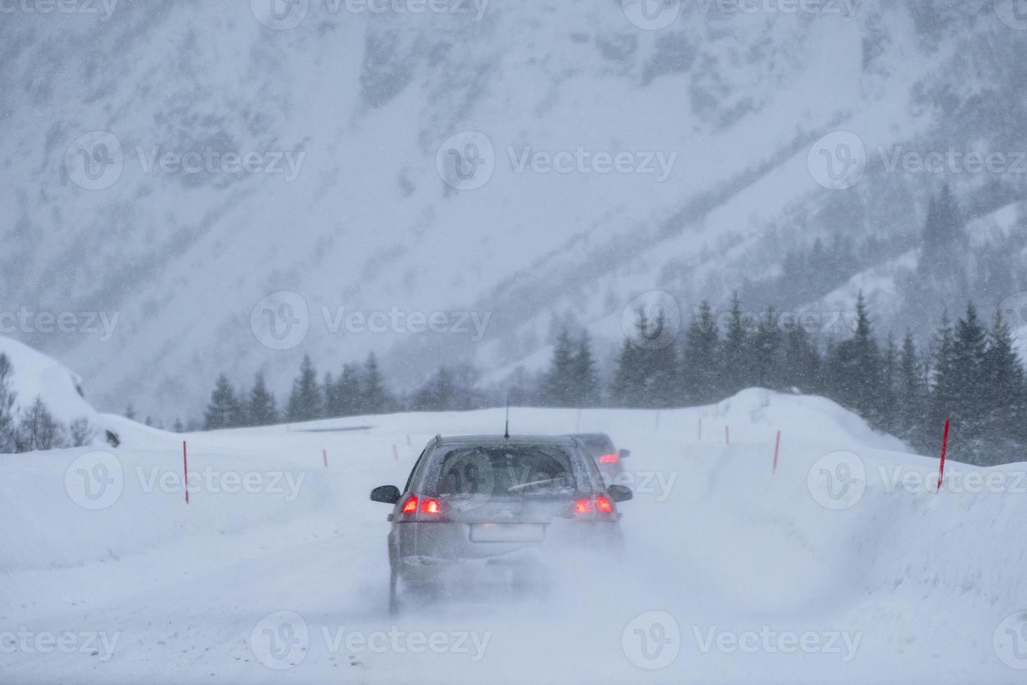 bakre bil kör försiktighet genom en snöstorm i dalen foto