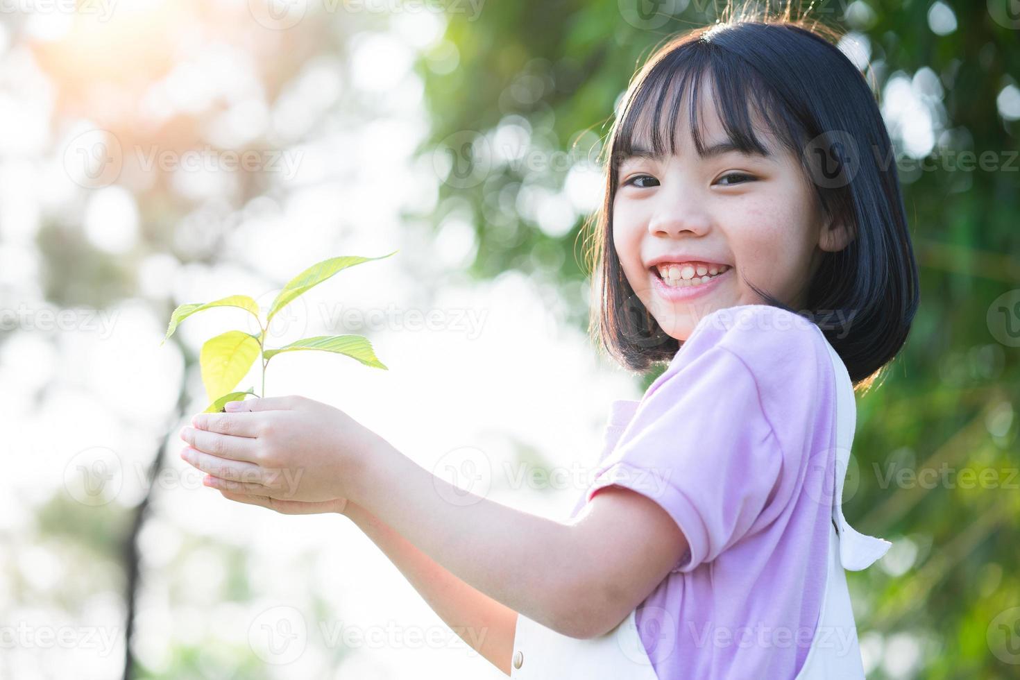 bild asiatisk liten flicka som håller en planta i handen foto