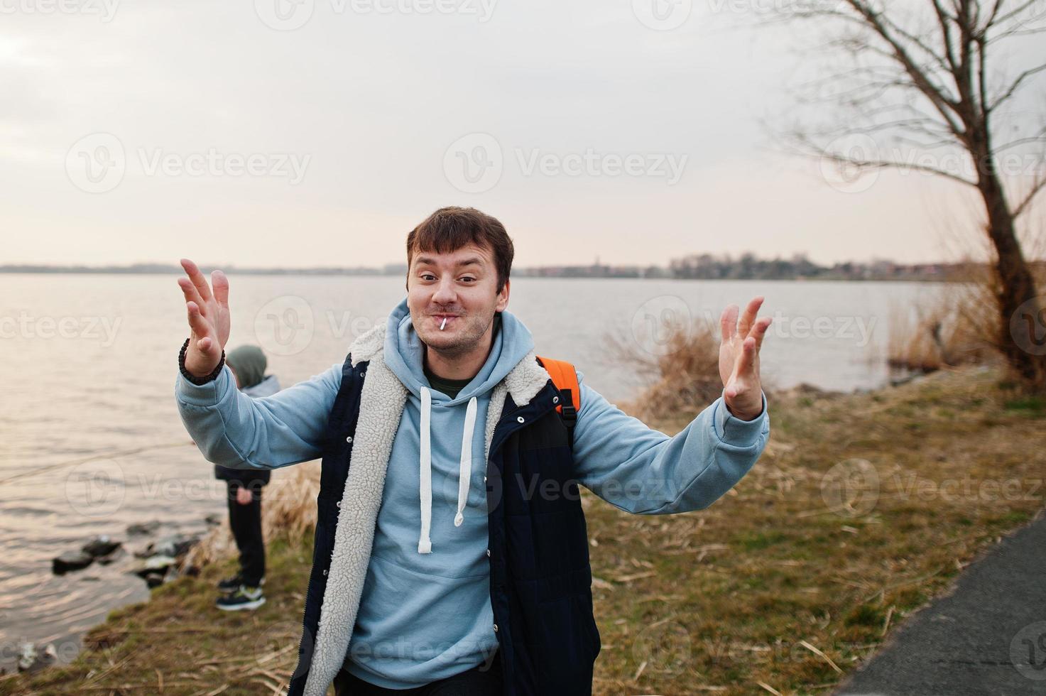 rolig man i blå hoodie med klubba, visar olika handrörelser. foto