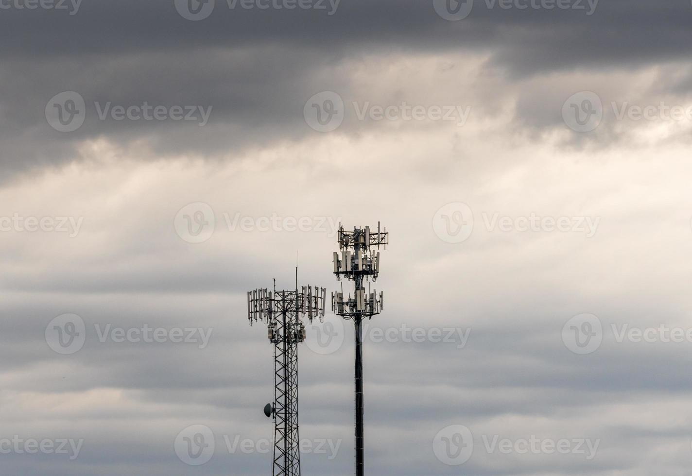 två mobiltelefontorn som tillhandahåller digital service till landsbygdsområden i molnig himmel foto