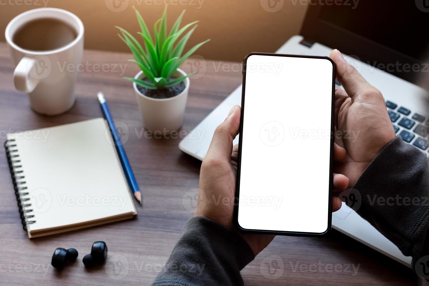 mockup kopia rymdtelefon, mannens hand som håller smartphone med tom vit kopia skärm för din reklam och meddelande eller information innehåll, mobil på skrivbordet på kaféet. foto