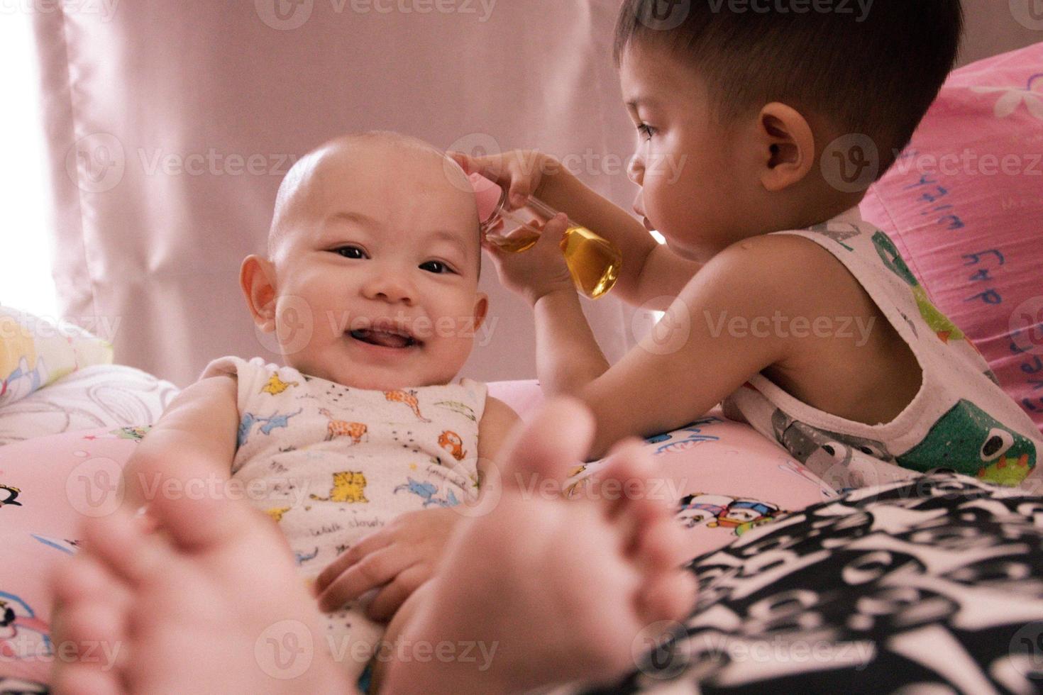den asiatiska systerbebisen leker med sin pojkebebis i vardagsrummet. foto