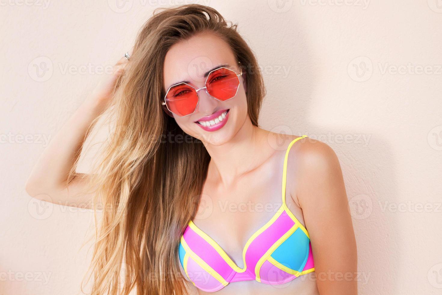 närbild av glad tjej i rosa solglasögon isolerade. sommarlov och rolig helg. sommartid koncept. leende ung kvinna i mode baddräkt. selektiv fokusering. strand sommar outfit. kopieringsutrymme foto