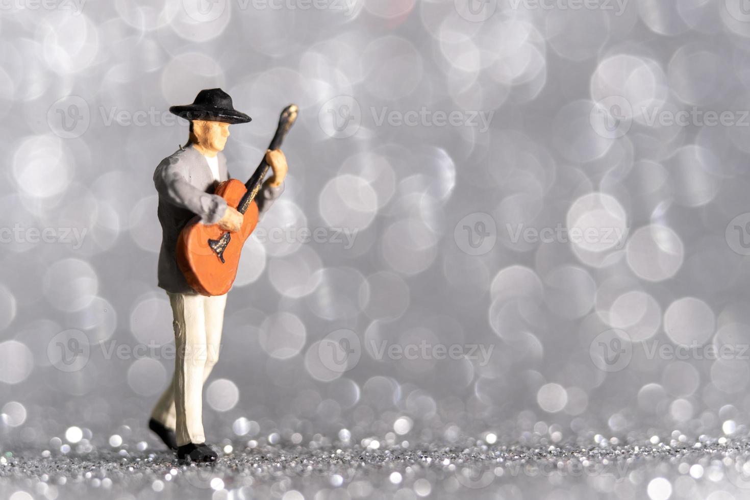 miniatyrmusiker med gitarr på bokeh bakgrund foto