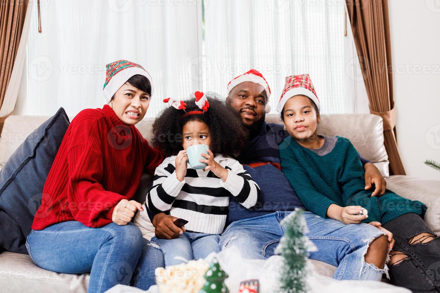 lycklig familj har kul att sitta tillsammans i soffan hemma. glad ung familj med barn som skrattar. afroamerikansk familj foto