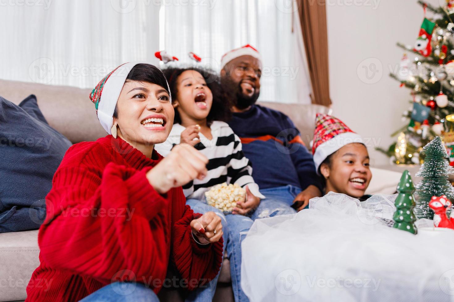 lycklig familj har kul att sitta tillsammans i soffan hemma. glad ung familj med barn som skrattar. afroamerikansk familj foto