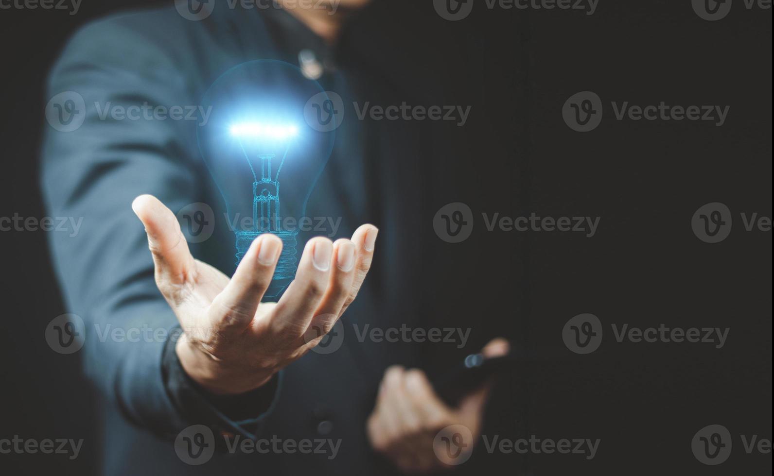 affärsman hand som håller glödlampa med finansdokument och verktyg. foto