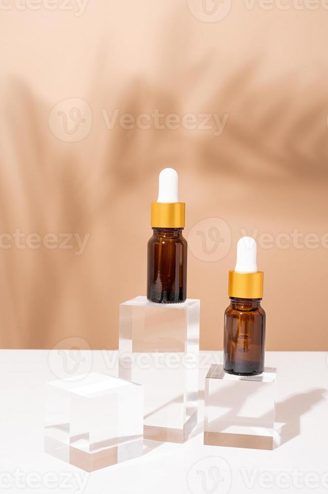 bärnstensfärgade droppflaskor i glas med en pipett med vit gummispets på glaspodium och beige bakgrund, mockupdesign foto