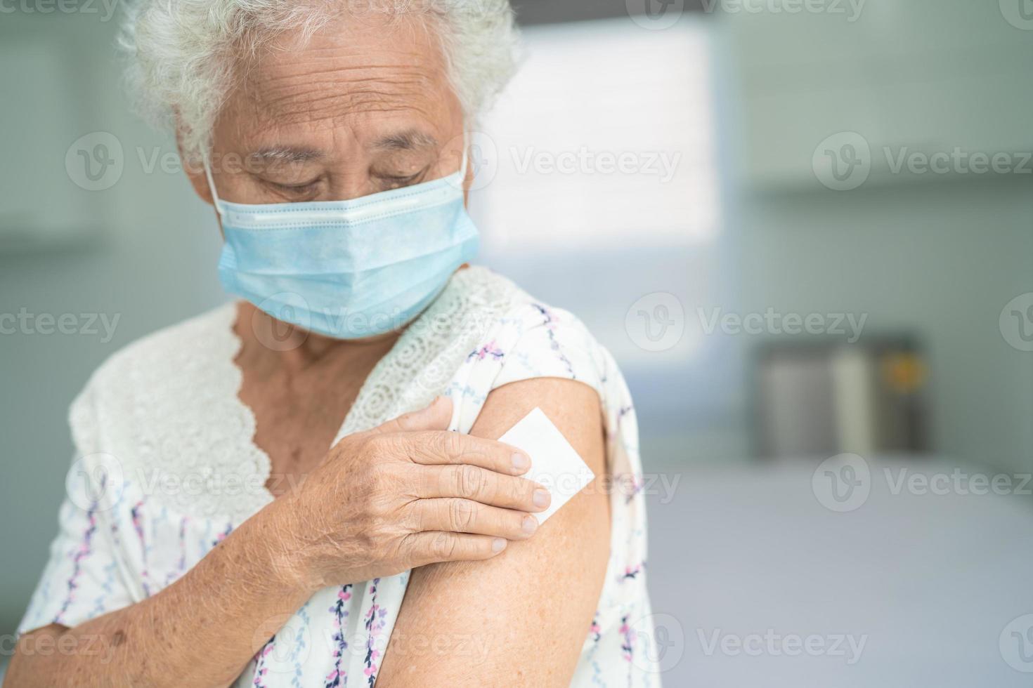 äldre asiatisk äldre kvinna som bär ansiktsmask får covid-19 eller coronavirusvaccin av läkare gör injektion. foto