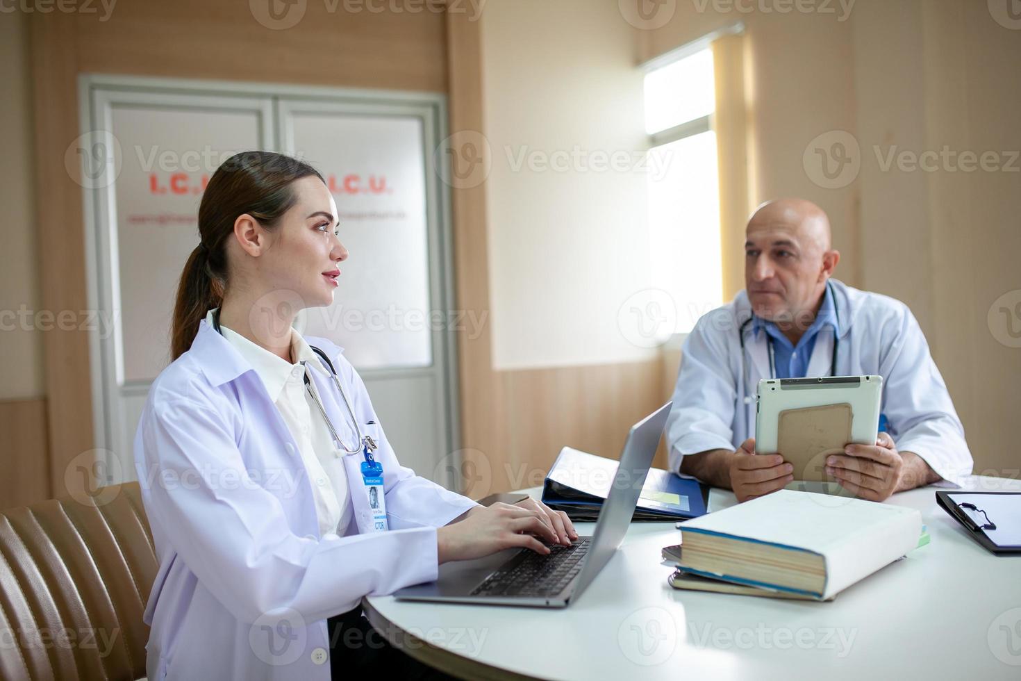 grupp läkare som konsulterar patientjournaler, äldre läkare och kollega diskuterar aktuell sjukdomsbehandling på arbetsplatsen. foto