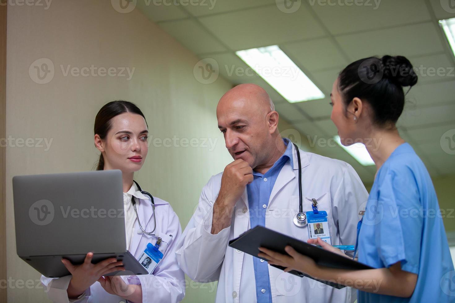 grupp läkare som konsulterar patientjournaler, äldre läkare och kollega diskuterar aktuell sjukdomsbehandling på arbetsplatsen. foto